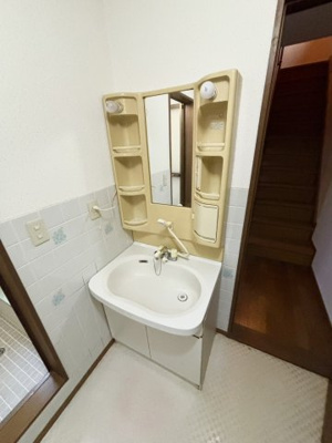 【独立洗面台】 | 鶴見区浜３丁目中古戸建 | 毎日の身支度に欠かせない、コンパクトな洗面台です。鏡の両サイドには収納スペースがあり、ご家族の洗顔用品やヘアケア用品をまとめて置くことができます。