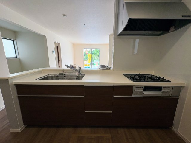 リーブルガーデン南城市佐敷新里・3号棟のキッチン|会話の弾む対面式のシステムキッチン／リビングの眺め