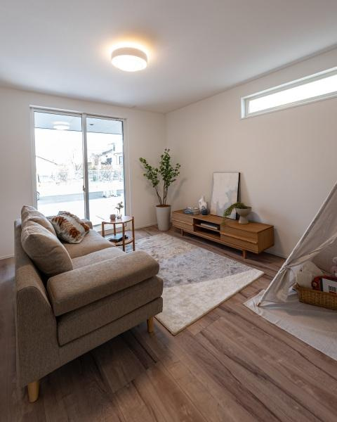 小佐井Ｎ新築の居間・リビング|広々としたリビングは木目調のフローリングが特徴的です。窓からの光が差し込み室内が明るい印象です。キッチンとリビングがつながっており使いやすい空間です。