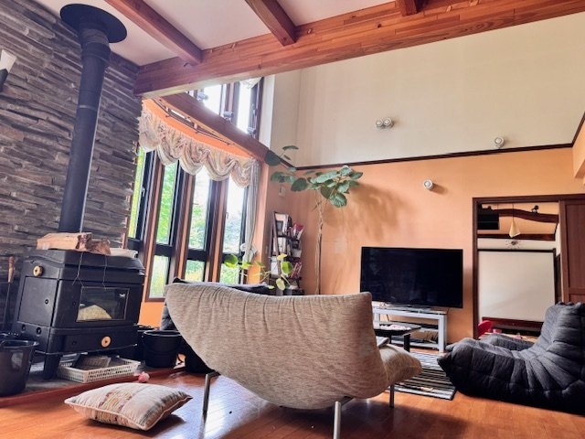 西軽井沢 追分 インナーガレージ付中古戸建の居間・リビング|開放感のある吹抜けと、暖炉が特徴的な、寛ぎのリビング