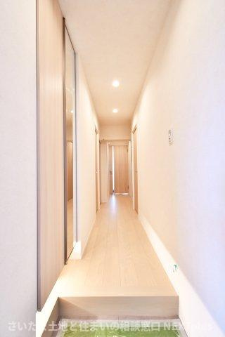 ライオンズマンション大宮指扇第二の玄関|玄関ドアの正面にはリビングの扉が設置されておりますので、急な訪問で玄関を開けた際室内が見えない設計です！木目調のフローリングと白い壁は統一感があり、間接照明がおしゃれでモダンな雰囲気の玄関です。