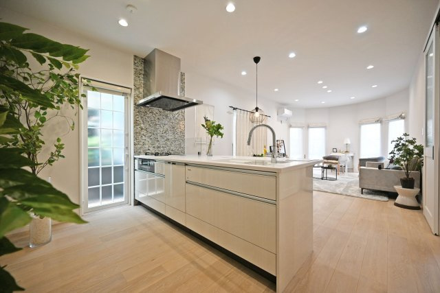 西宮市南甲子園3丁目新築未入居戸建│3SLDK+駐車2台可(車種制限有)のキッチン|1階LDKをキッチンユニット越しに撮影した内観写真です。フルフラットの対面式オープンキッチンを採用しているため視界は広く、ご家族間やご来訪者とのコミュニケーションも一体的に取り易くなっております。