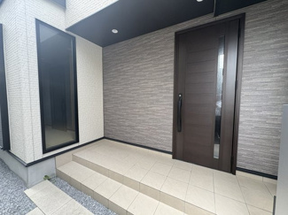 【玄関】 | GRAN　FELIDIA川口市八幡木 | 濃いブラウンの玄関ドアと、横長のタイル調、石目調の壁の組み合わせが、重厚感と高級感を演出するモダンなデザインです。