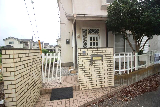 小山市粟宮の外観|白いタイルの門柱とフェンスが印象的な玄関アプローチ。植栽もあり、訪れる人を明るく迎えてくれます。