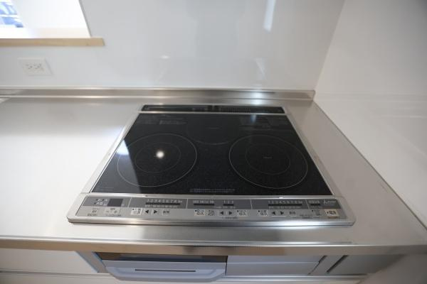 荏隈第3-2号棟のキッチン|明るい色合いのフローリングと壁がキッチン全体を開放的な雰囲気にしています。窓から自然光がしっかりと差し込み清潔感があります。シンプルなデザインでお手入れもしやすそうです。