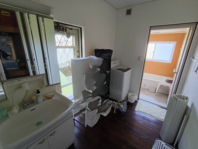 西条市周布892-5　中古住宅の洗面所|濯機を置いても十分なゆとりがある洗面脱衣所。朝の身支度が重なっても家族同士でスムーズに使える広さ。窓があるため湿気が逃げやすく、洗濯物の一時干しスペースとしても活用できる家事に便利な多目的空間。