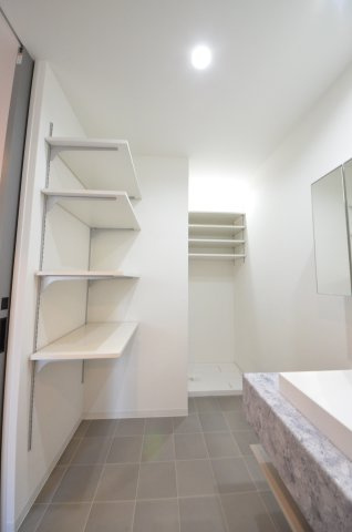 旭一丁目の収納|清潔感あふれるシャワー付洗面台と洗面室。
収納棚のある余裕のスペース。