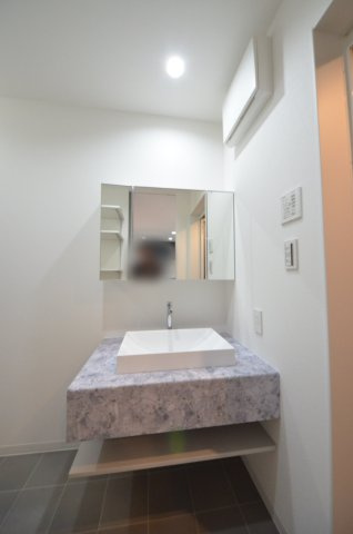 旭一丁目の独立洗面台|清潔感あふれるシャワー付洗面台と洗面室。
収納棚のある余裕のスペース。