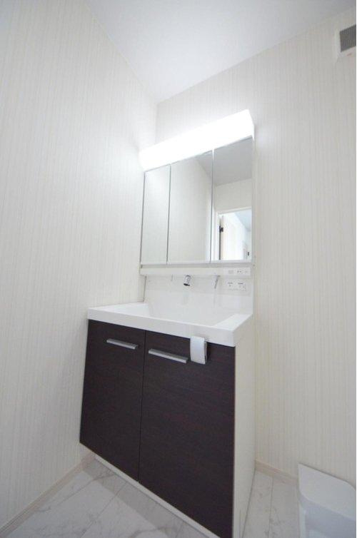 宮島口上1丁目の洗面所|清潔感あふれる白を基調としたシャワー付洗面台と洗面室。収納棚もある余裕のスペース。窓もあり明るく通気も良いです。