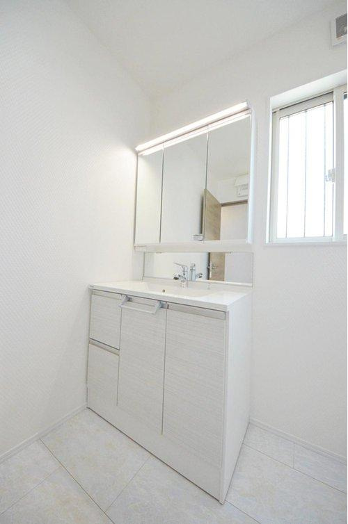 国信2丁目の洗面所|清潔感あふれる白を基調としたシャワー付洗面台と洗面室。収納もある余裕のスペース。窓もあり明るく通気も良いです。