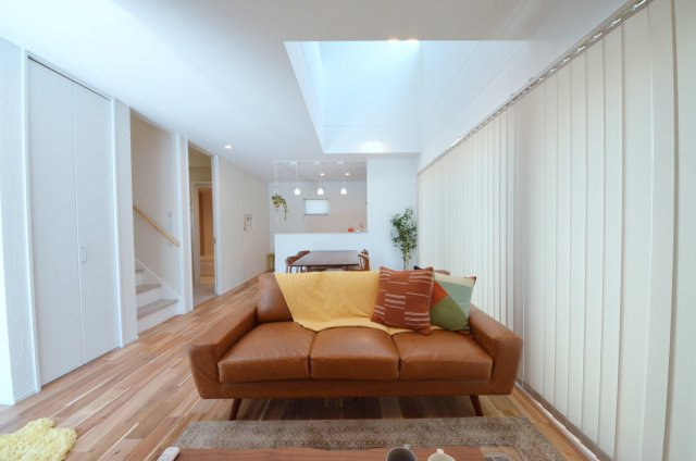 府中町八幡一丁目の居間・リビング|吹き抜けのある広く明るいリビング空間。オープンタイプの対面式キッチンでリビングが隅まで見渡せます。キッチンにいながら小さなお子様にも目が届き安心です。