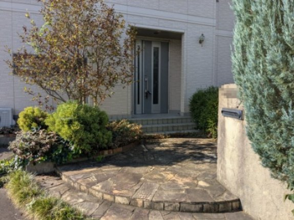 中古戸建　上大島町のエントランス|豊かな植栽と石畳のアプローチが魅力的！温かみのあるデザインで家族やゲストをやさしく迎える玄関です。