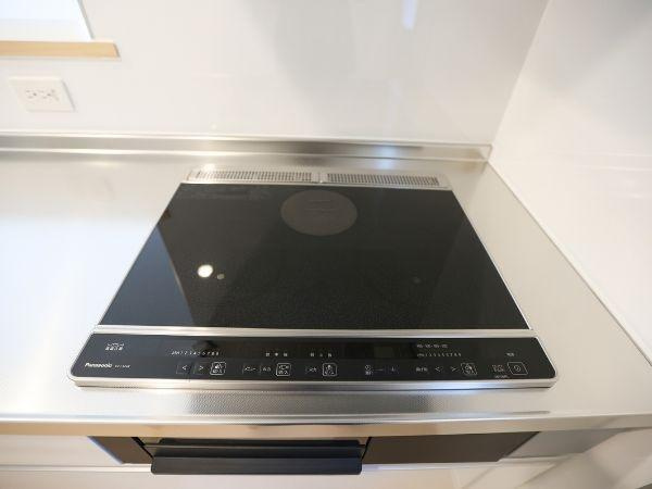 久原中央第4-1号棟のキッチン|スタイリッシュなデザインのIHクッキングヒーターが設置されています。お手入れしやすいフラットな天板が特長です。キッチン全体がすっきりとまとまった印象です。作業がしやすい広めのカウンターとなっています。