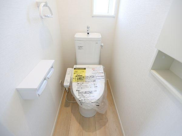 久原中央第4-1号棟のトイレ|シンプルで清潔感のあるトイレです。窓があるため自然光が入りやすい設計です。壁付け収納も備わっており利便性を感じられます。床材の色合いが明るくすっきりとした空間です。