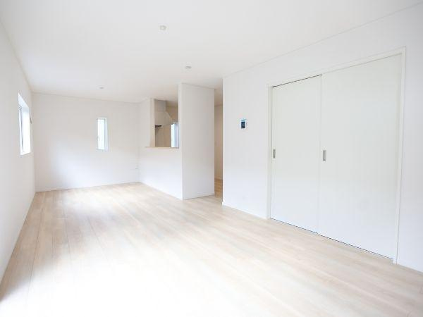 久原中央第4-1号棟の居間・リビング|リビングは明るく開放的な空間です。白を基調とした内装が広がりを感じさせます。フローリングが清潔感を演出しています。大きめの引き戸が使い勝手を高めています。