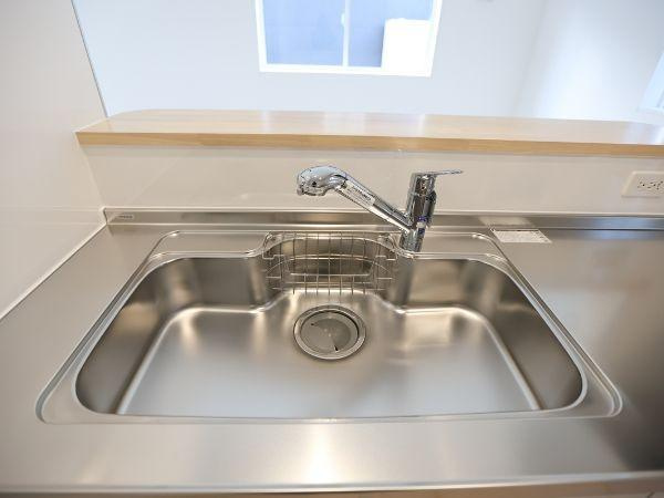 久原中央第4-1号棟のキッチン|キッチンのシンクは広々とした設計で清潔感のあるステンレス素材です。蛇口はシンプルなデザインで使いやすさが感じられます。明るい光が差し込む開放的な空間が魅力です。収納スペースも確保されています。