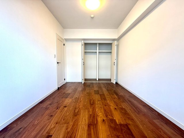 ディアコート横浜関内の玄関|大きなクローゼットを備えた洋室。木目の床材と白壁が調和し、シンプルかつ洗練された住空間です。