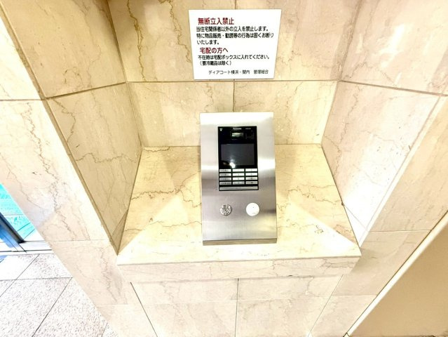 ディアコート横浜関内の防犯設備|大理石調の壁に設置されたオートロックシステム。安心と格式を兼ね備えた、上質な住まいの顔です。