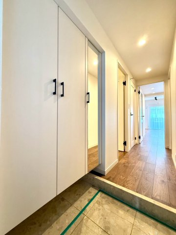 ディアコート横浜関内の玄関|大容量シューズボックスと姿見を備えた玄関。石調タイルと木の温もりが調和する、洗練された迎賓空間です。