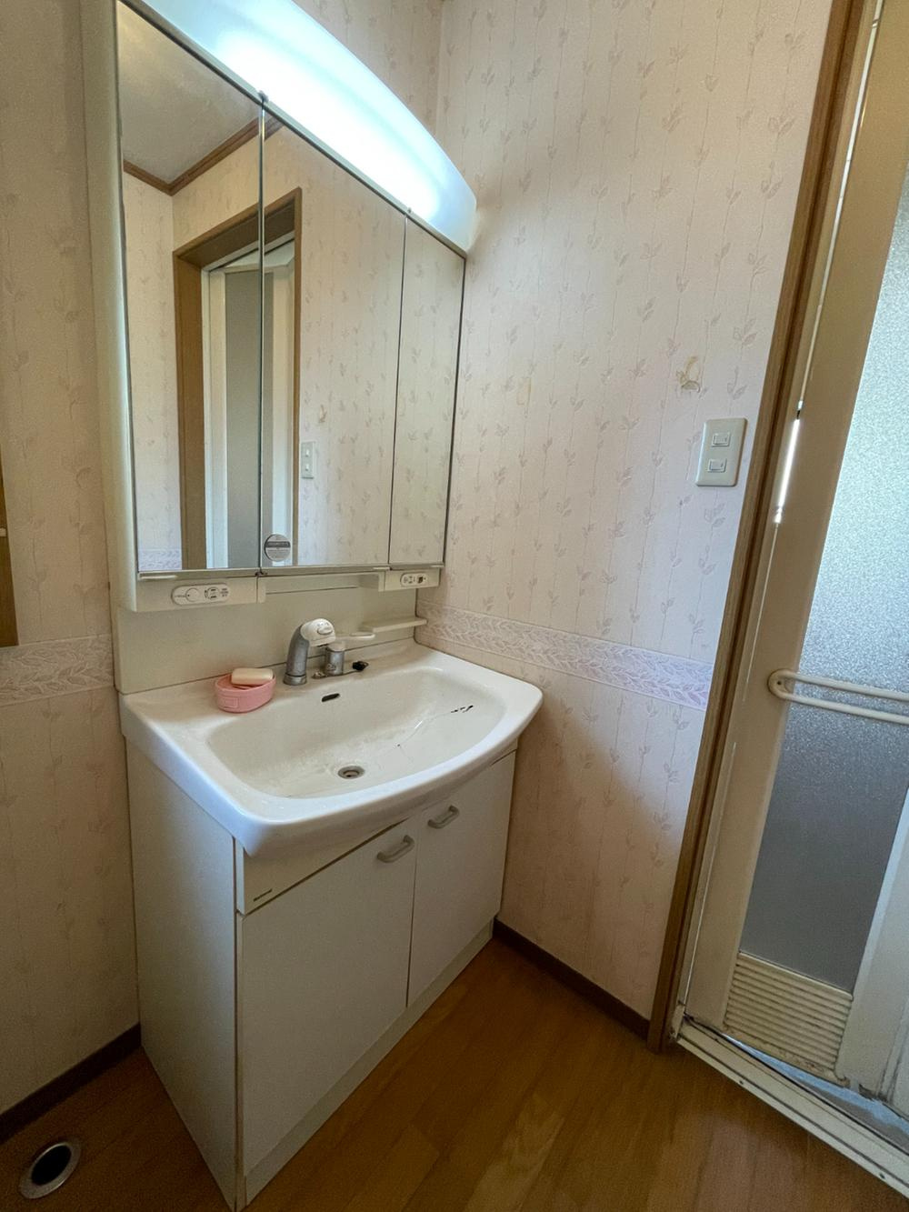 明石市魚住町長坂寺戸建の独立洗面台|【洗面化粧台】
身支度やヘアセットの際に重宝する三面鏡タイプの洗面化粧台です。洗面ボウル下、鏡裏に収納スペースがあり、洗面用品や化粧品、ストック類などを整理できます。