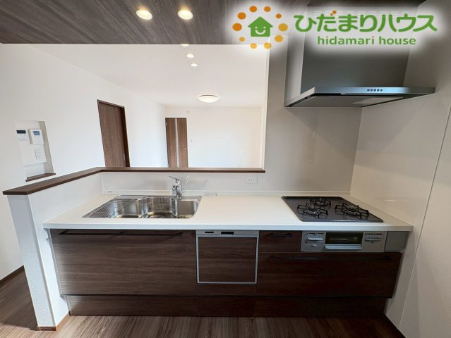 深谷市萱場　第10期　新築一戸建て　ワイウッドコート　06のキッチン|手元が隠れるスマートな立ち上がりを設けたシステムキッチンです！三口コンロとワイドなシンクが備わっており、日々のお料理や片付けが手際よく進められるほか、お掃除がしやすい素材なのも嬉しいポイントです♪