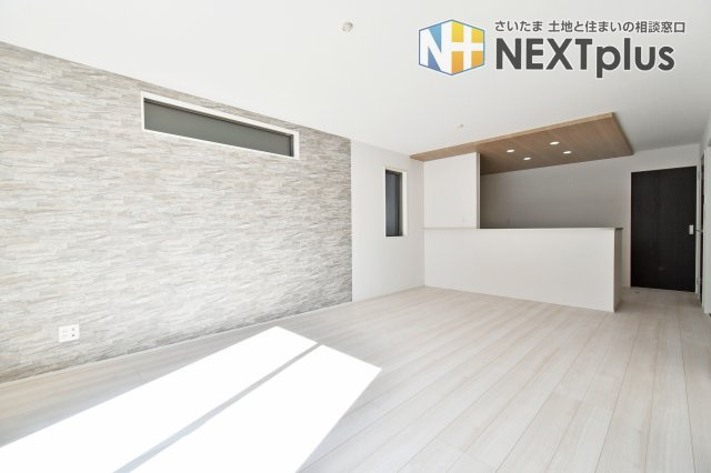 久喜市青葉５期全２棟　１号棟の居間・リビング|【LDKアクセント】アクセントクロスと高窓で空間にメリハリ。壁面を活かして収納や飾り棚も検討できます。テレビ配線やコンセント位置、窓の開閉、日中の明るさや反射は現地で確認を。配置相談も可。