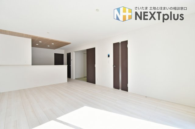 久喜市青葉５期全２棟　１号棟の居間・リビング|【LDK別角度】キッチンからリビングを見渡せるレイアウトで家族の様子が分かりやすい空間。ダイニング配置や回遊性がポイントです。通路幅、照明位置、コンセント数は現地で動線確認を。家具の寸法も。