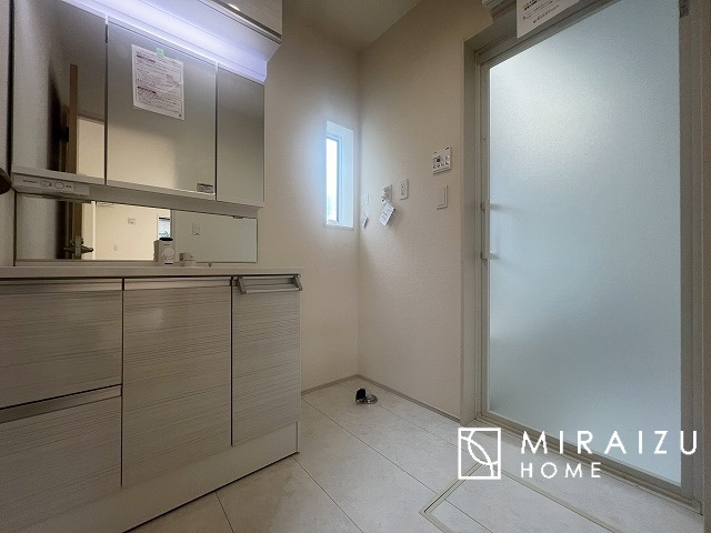 【洗面所】 | 洗濯機置き場と脱衣スペースもしっかりと確保されている洗面室、洗面コーナーは、窓から陽も差し明るく開放的な造りです。家事導線も良いので洗濯物やお湯はりもストレスフリーに毎日家事を楽しめそうです。
