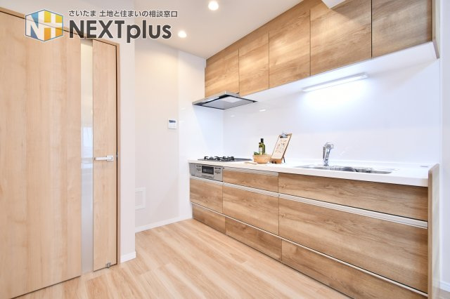 日建シェトワ浦和のキッチン|木目基調の吊戸棚付きシステムキッチンです。上にも下にもたくさん収納出来ますので、別途で食器棚がなくてもたくさん収納する事ができます！ライトもありますので、お料理中の手元もしっかり照らしてくれます。