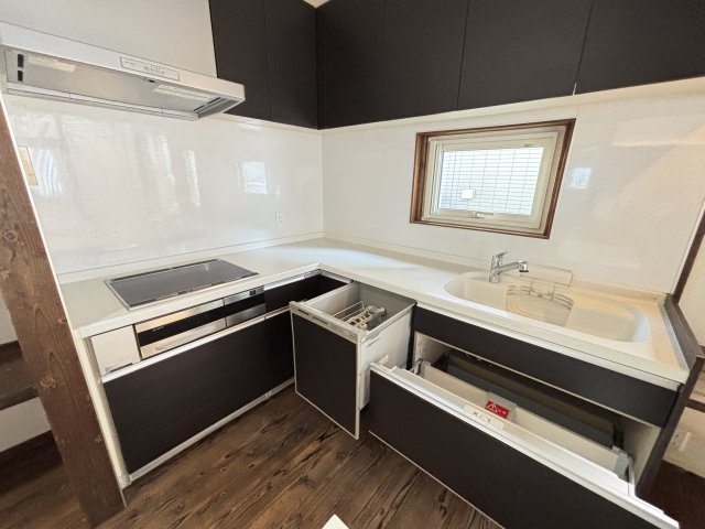 中古戸建　　伴南５丁目のキッチン|ダークブラウンのシックな扉と、白いワークトップのコントラストがおしゃれなキッチンです。木目の天井や窓枠が温かみを添え、落ち着いた雰囲気の中で毎日のお料理を楽しめます。