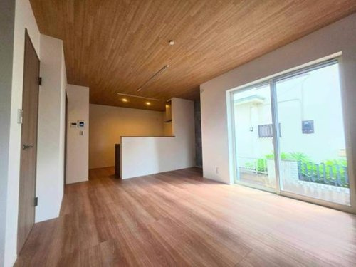 小川町１丁目新築住宅の居間・リビング|木目調の天井と床が統一感を演出しています。開放感のある大きな窓からは自然光がたっぷり入ります。キッチンとリビングが程よく区切られているため様々なレイアウトが可能です。