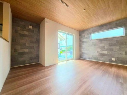 小川町１丁目新築住宅の居間・リビング|明るい光が差し込むリビングは開放感があります。ウッド調の天井と床が調和し落ち着いた雰囲気です。アクセントウォールが空間を引き締めます。大きな窓からは外の景色も楽しめます。シンプルで使いやすい空間です。