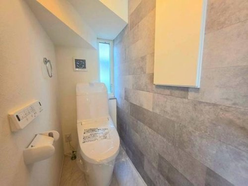 小川町１丁目新築住宅のトイレ|明るく清潔感のあるトイレ空間です。壁面には落ち着いた色合いが使用されています。収納スペースもしっかり確保されています。操作パネルが壁付けで使いやすいです。通常の使用に安心感を与える設計がされています。