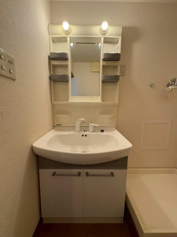 【独立洗面台】 | パレス南塚口1号棟 | 鏡の横に棚があり、タオルなどを置ける使いやすい洗面化粧台。明るい照明で朝の身支度もスムーズです。