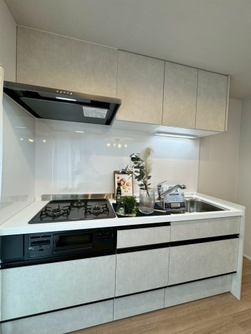 枚方三矢第一住宅壱号棟のキッチン|三口コンロに広々調理スペースございます。収納力のあるキッチンで調理器具もすっきり収納可能です。