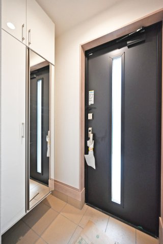 ハートフルタウン浜町新築一戸建て│2SLDK・3LDK+駐車1台可の玄関|1階玄関をホール側から撮影した内観写真です。 シンプルな玄関扉にシューズボックス、小窓を配置したオーソドックスな玄関です。