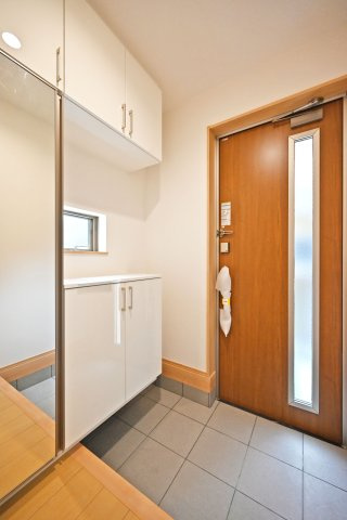 ハートフルタウン浜町新築一戸建て│2SLDK・3LDK+駐車1台可の玄関|1階玄関をホール側から撮影した内観写真です。 シンプルな玄関扉にシューズボックス、小窓を配置したオーソドックスな玄関です。