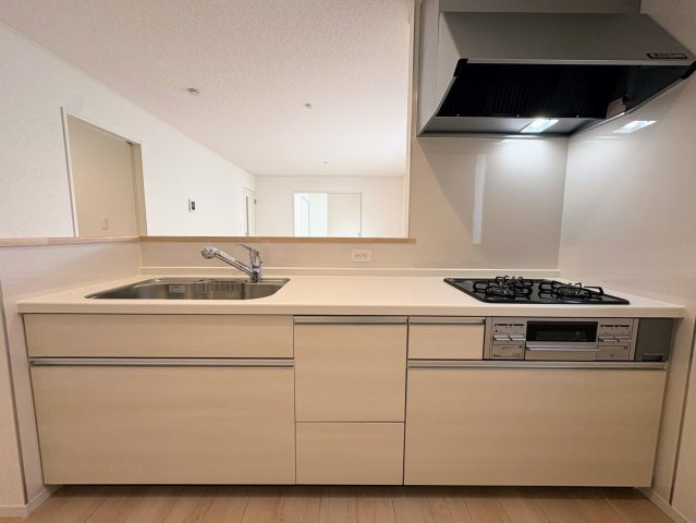 クレイドルガーデン南城市大里稲嶺 第4・１号棟のキッチン|レンジフード＆ガスコンロ３口＆作業台＆流し台／キッチンからダイニングの眺め