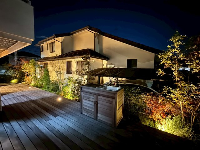 狭山市柏原中古戸建のその他|夜のライトアップがウッドデッキと植栽を美しく照らしまるで旅館のような特別な雰囲気に。ガーデンシンク付きで夜風を感じながらの食事や団らんなど贅沢な外時間を楽しめる住まいです。