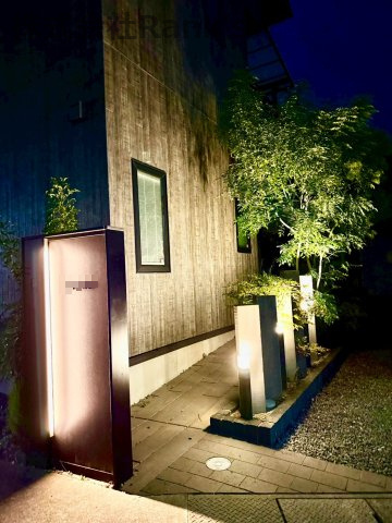 明石市大久保町茜3丁目のエントランス|夜のエントランスは、黒と木目調のモダンな門柱と家のシンボルツリーの植栽がライトアップしてラグジュアリーな雰囲気に♪