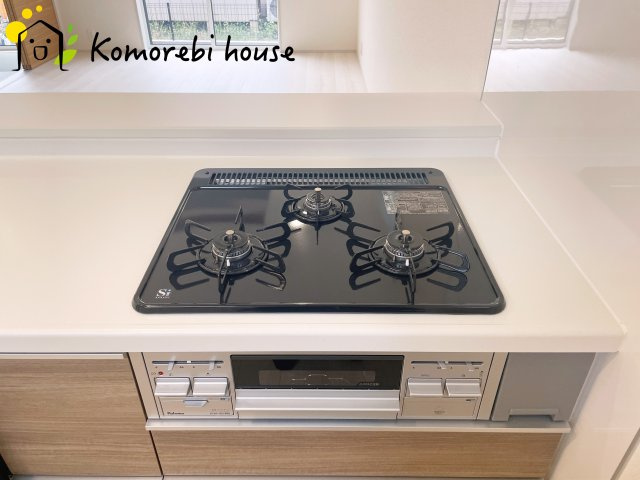 上尾市原市北1丁目　新築一戸建て　ブルーミングガーデン　01のキッチン|同時調理が叶う3口コンロと便利なグリル付き。忙しい朝のお弁当作りも、夕食の複数メニューもスムーズにこなせる頼れる設備です。															
