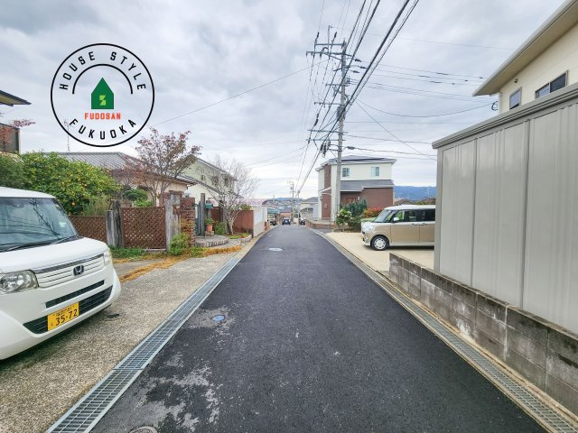 古賀市千鳥6丁目第1-2棟（2号棟）の前面道路含む現地写真|前面道路は閑静な住宅地をはしる車通りの少ない道路。お車の出し入れが苦手なママや小さなお子様にも安心ですね。しっかり舗装もされているので、ベビーカーや自転車で通っても快適に通行できます。