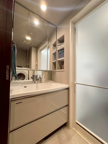 イーグルコート大津フロント 5Fの洗面所|白を基調とした清潔感のある洗面脱衣室。リネン庫や棚など、収納も充実しています。