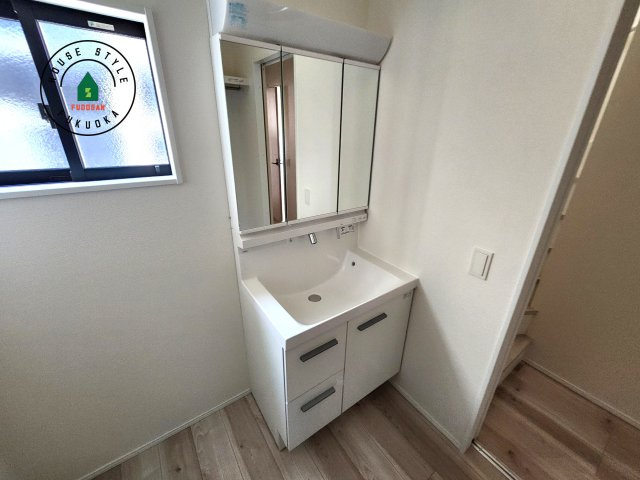 福岡市東区奈多1丁目第2-6棟（3号棟）の内観：施工例|毎日使うものだから清潔な空間を保ちたい水回り。洗面にはそんな願いを解消させてくれる収納アイデアが満載です。三面鏡の裏側にはキャビネットが現れ小物から背の高い物まで収納できます。