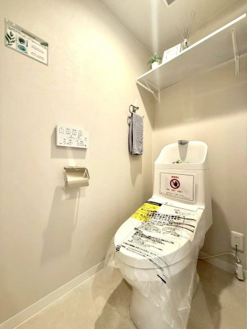 ニックハイム綱島第5のトイレ|淡いベージュトーンでまとめられたトイレ。吊戸棚付きで収納力も備え、上品で落ち着きのある空間が広がります。