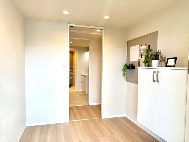 ニックハイム綱島第5の玄関|白を基調とした清潔感あふれる玄関。飾り棚にはグリーンが映え、訪れる人を優しく迎える上品な空間です。