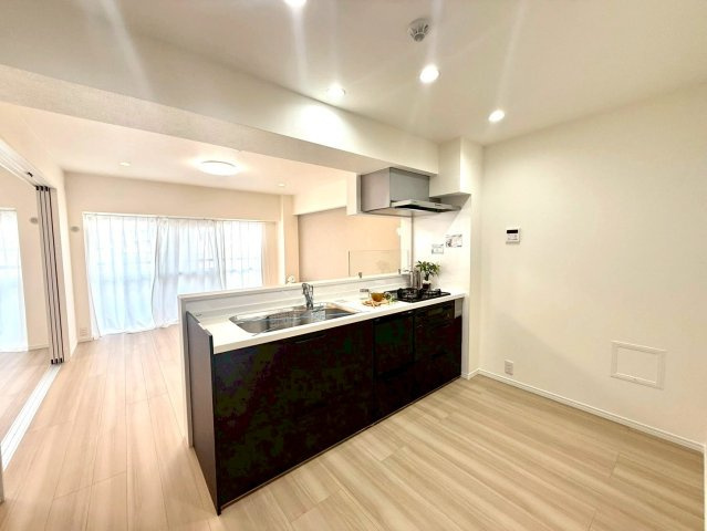 ニックハイム綱島第5の居間・リビング|白と黒のコントラストが美しいシステムキッチン。リビングを見渡せる開放的な設計で、家族との会話が弾みます。