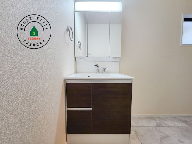 福岡市東区若宮4丁目第3-5棟（3号棟）の内観：施工例|毎日使うものだから清潔な空間を保ちたい水回り。洗面にはそんな願いを解消させてくれる収納アイデアが満載です。三面鏡の裏側にはキャビネットが現れ小物から背の高い物まで収納できます。