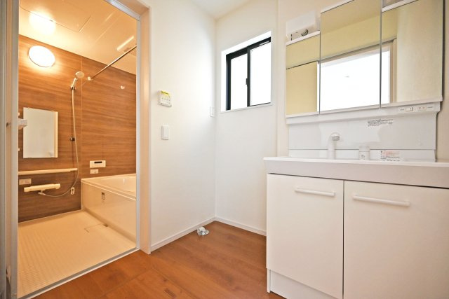 テラシエ池尻新築3丁目一戸建て│4LDK+並列駐車2台可(車種制限有)丁目の独立洗面台|洗面室に入ってすぐの内観写真です。900mm幅のシャンプードレッサーを導入しており、広々と使用できます。十分な明るさのある2照明を採用し、朝支度もスムーズに進みます。