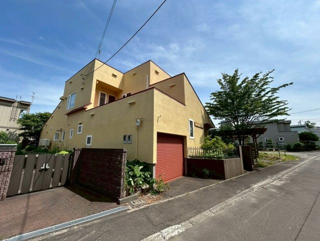 里塚1条3丁目戸建の外観|心が明るくなるような外壁色と庭木によって作られたプライバシーに配慮された外観は、都心部の喧騒を忘れる落ち着いたご生活を演出します。